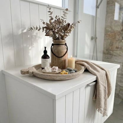 Bathroom counter with decorative items including a vase with dried plants, bottles, and a candle.