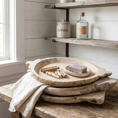 Wooden trays with items on a wooden surface near shelves with bottles and containers.