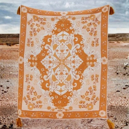 Decorative orange and white patterned blanket on a rocky surface with a desert background