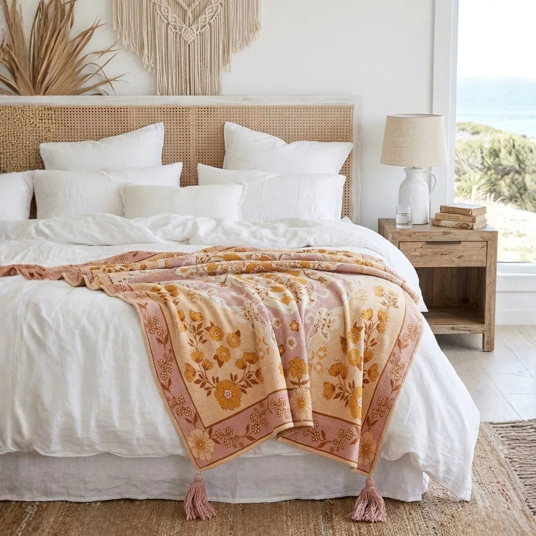 Bedroom with a bed featuring a floral blanket, white pillows, and a wooden nightstand.