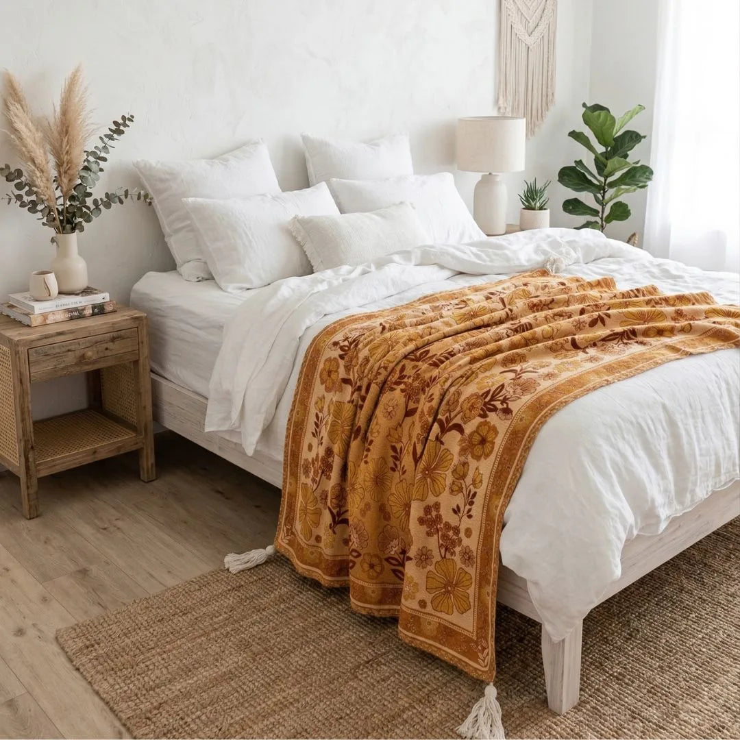 Bedroom with a bed featuring a floral blanket, wooden nightstand, and decorative elements.