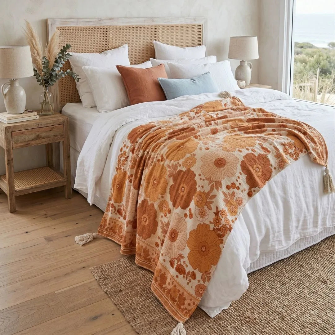 Bedroom with a bed featuring an orange floral blanket and white bedding, wooden nightstands, and lamps.