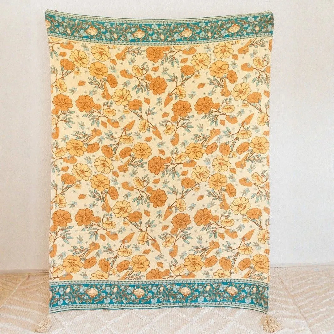 Floral patterned throw blanket with orange flowers on a beige background
