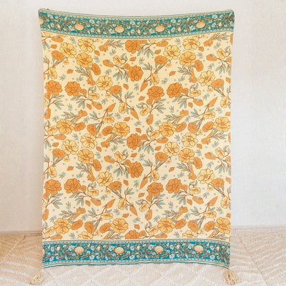 Floral patterned throw blanket with orange flowers on a beige background