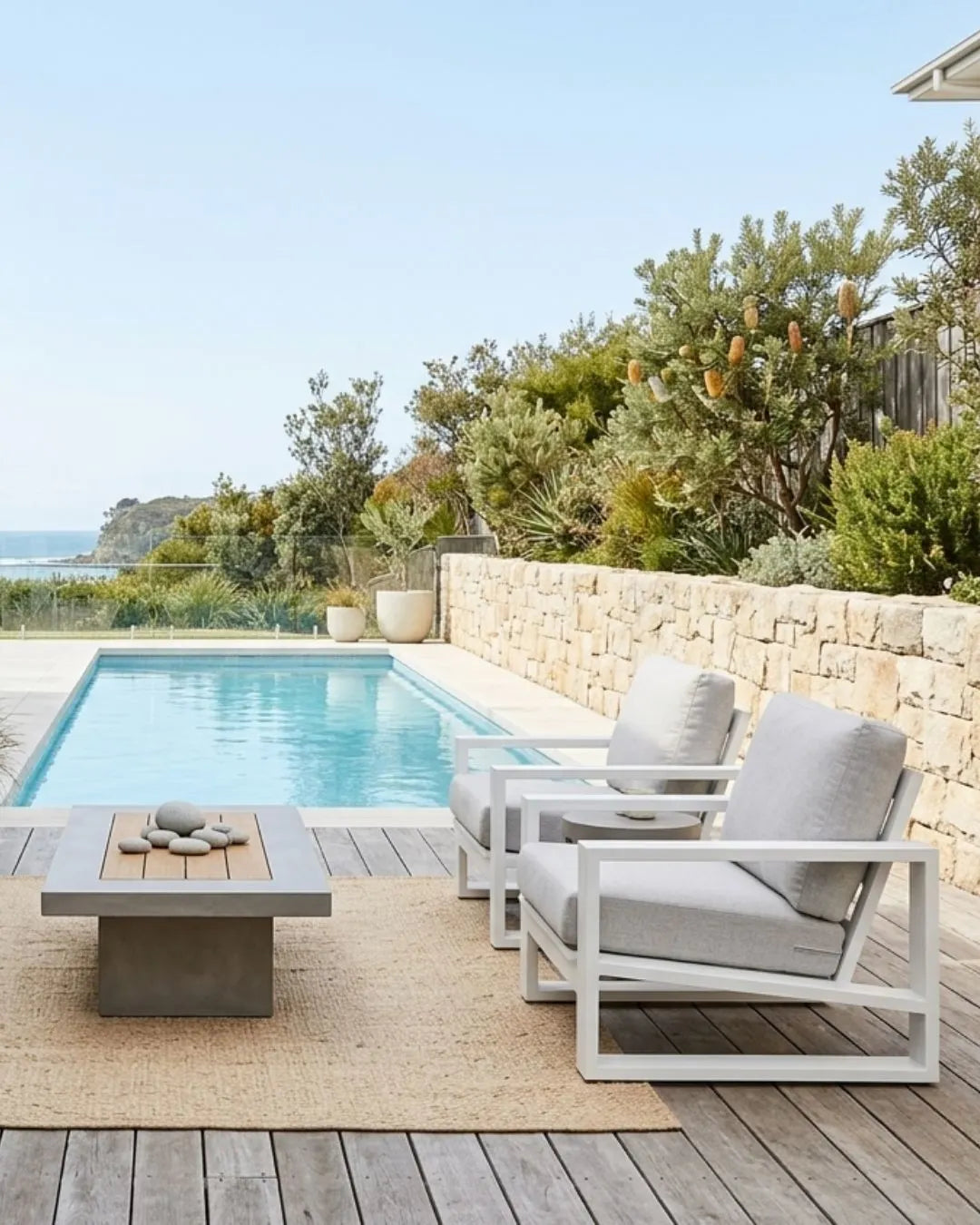 Outdoor patio set with chairs and table near a pool with a scenic view.