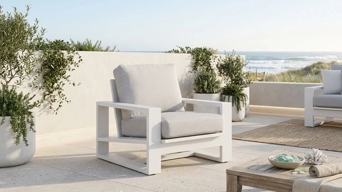 Outdoor patio furniture set with white chairs and a coffee table on a sunny day.