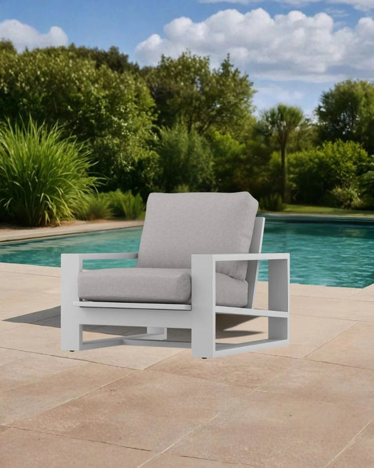 Gray outdoor chair with white frame by a pool with greenery in the background