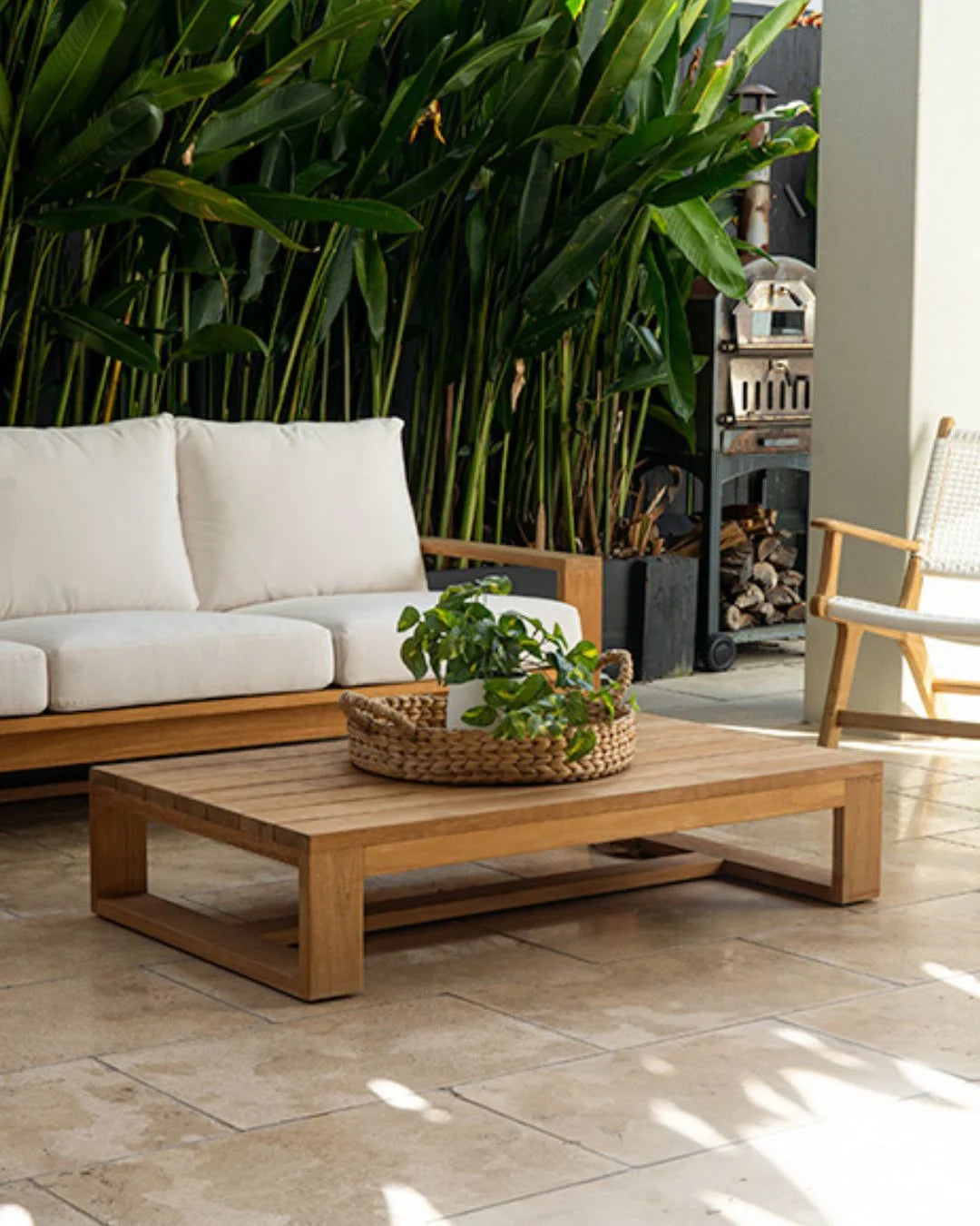 Outdoor patio with wooden furniture, white cushions, and potted plants.