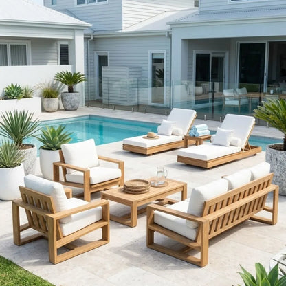 A 5-piece outdoor patio furniture set with light oak wood frames and white cushions, arranged around a matching coffee table on a tiled patio next to a swimming pool.