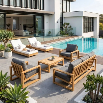 Modern outdoor patio furniture set including a wooden slat sofa, two armchairs with gray cushions, a matching coffee table, and two white lounge chaise lounges beside a swimming pool.