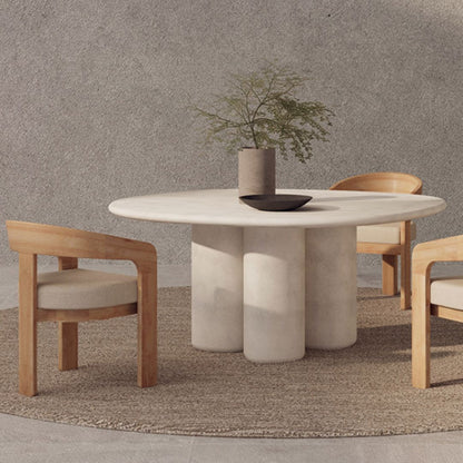 Organic Round stone dining table with wooden chairs against a textured wall.