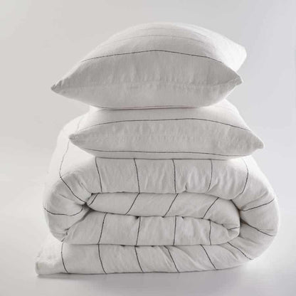 Stack of french linen bedding, white with black stripes .