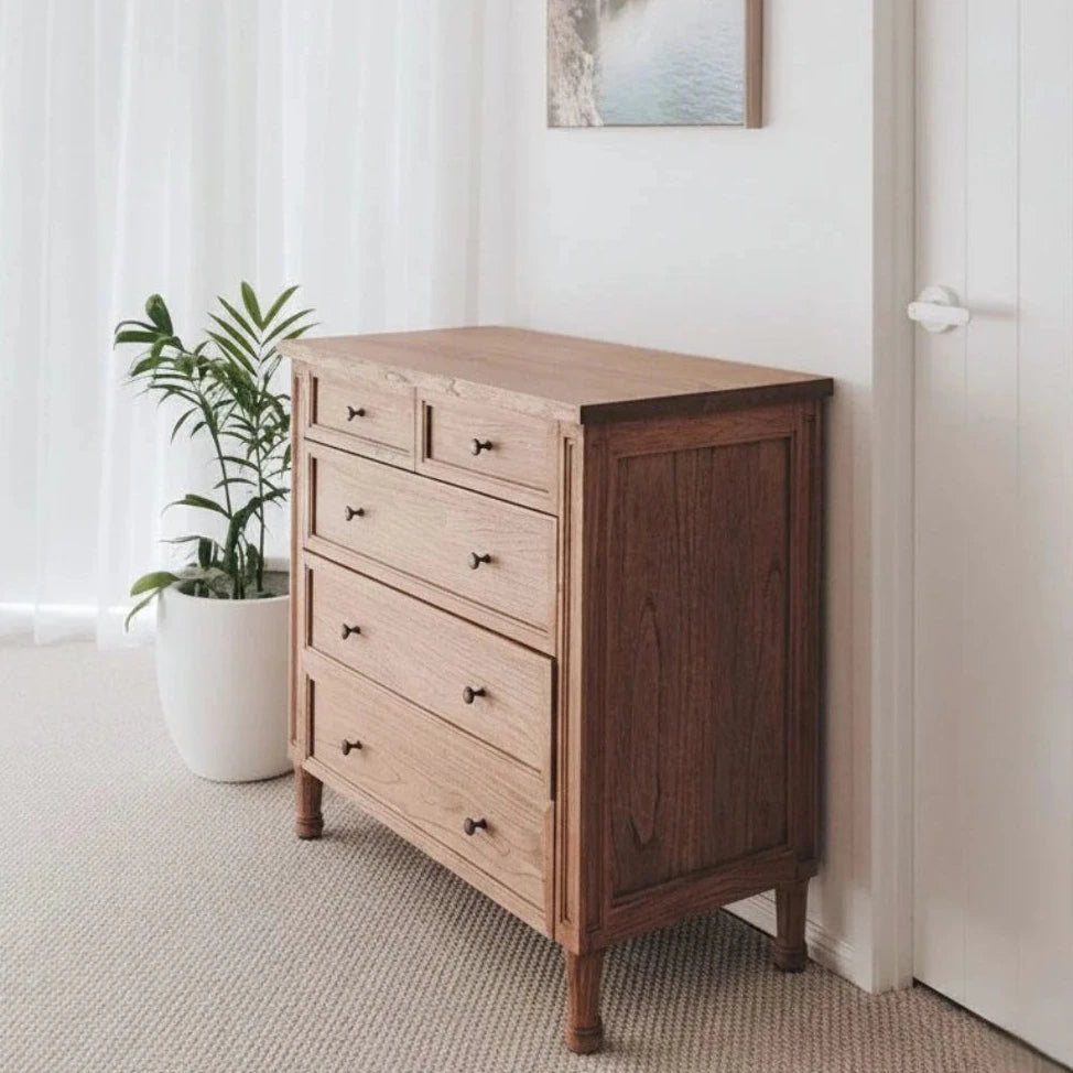 Wooden dresser with a plant in a room with white walls and a door.