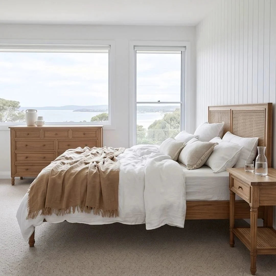 Bedroom with wooden bed, dresser, and nightstand with a view of water.