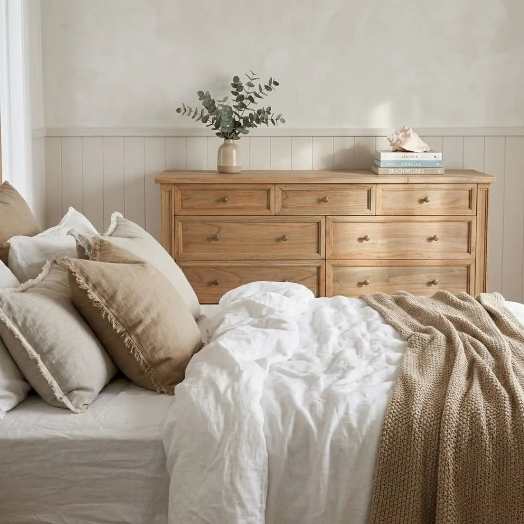 Bedroom with wooden dresser and bed with pillows and blanket