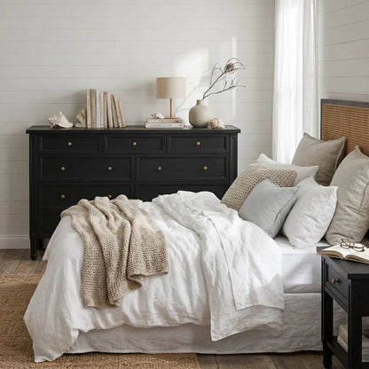 Neatly made bed with white bedding and beige throw blanket in a bedroom setting.