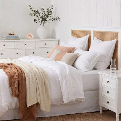 Neatly made bed with white bedding and colorful pillows in a bedroom setting.