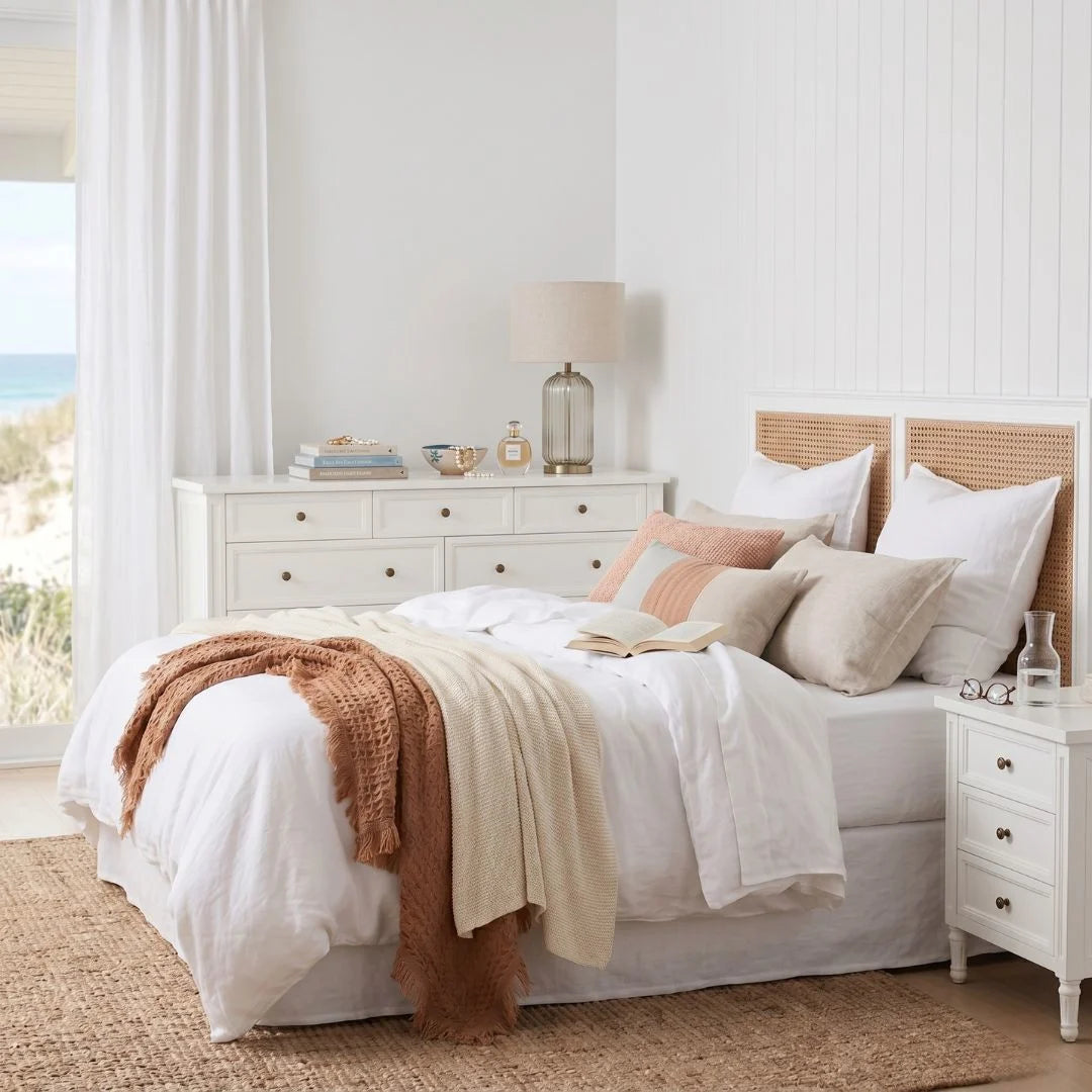 Neatly made bed with white bedding and decorative pillows in a bright bedroom.