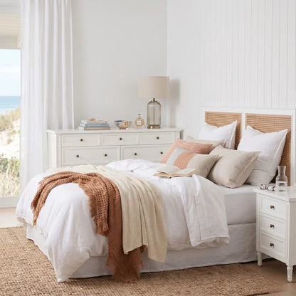 Neatly made bed with white bedding and decorative pillows in a bright bedroom.