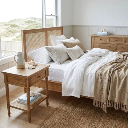 Bedroom with wooden bed and side table, white bedding, and natural light.