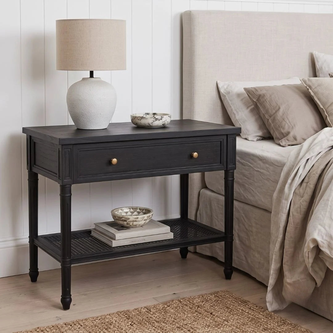 A black nightstand in a styled bedroom setting