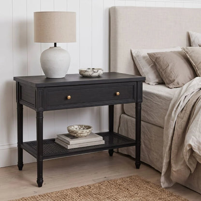 A black nightstand in a styled bedroom setting