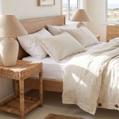 Neatly made bed with white bedding and beige pillows in a bright bedroom.