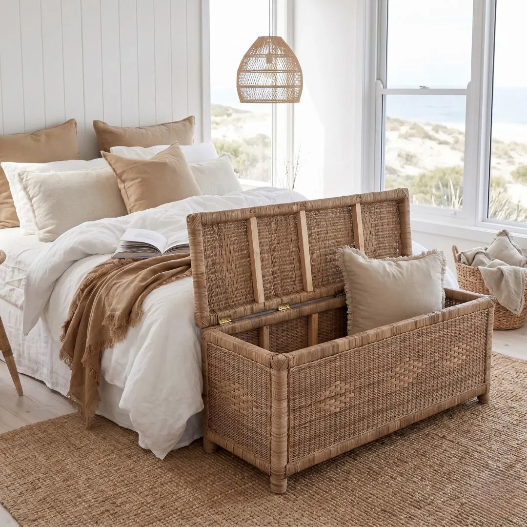 Wicker storage chest in a bedroom with a bed and pillows.