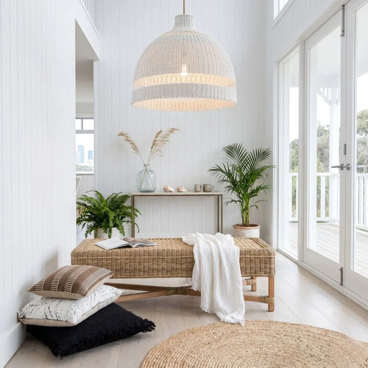 Modern interior with wicker bench, pillows, and plants in a bright room.