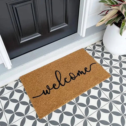 Doormat with 'welcome' text on a patterned floor in front of a black door.