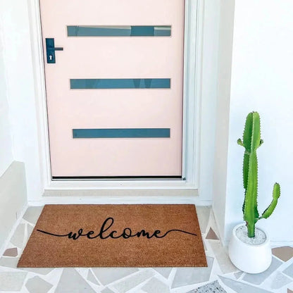Doormat with 'welcome' text in front of a door with a pink background