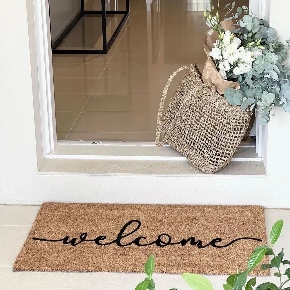 Doormat with 'welcome' text in front of a glass door with a basket of flowers.