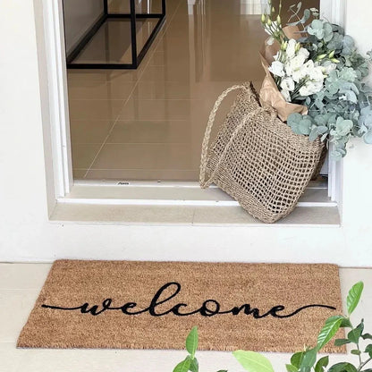 Doormat with 'welcome' text in front of a glass door with a basket of flowers.