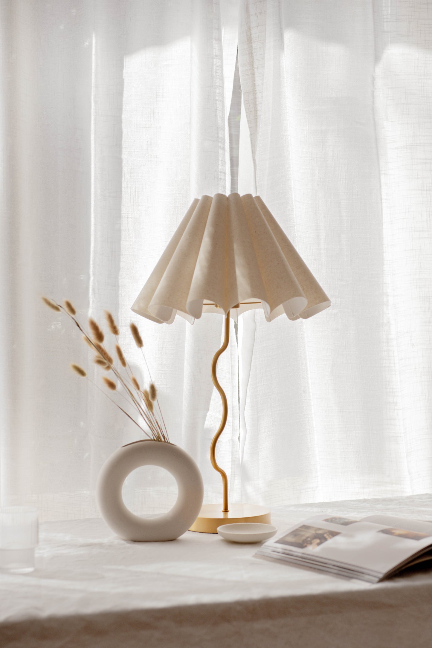 Beige lamp on a table with a white curtain in the background