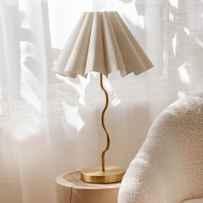 Cora lamp on a wooden side table with a soft white curtain in the background