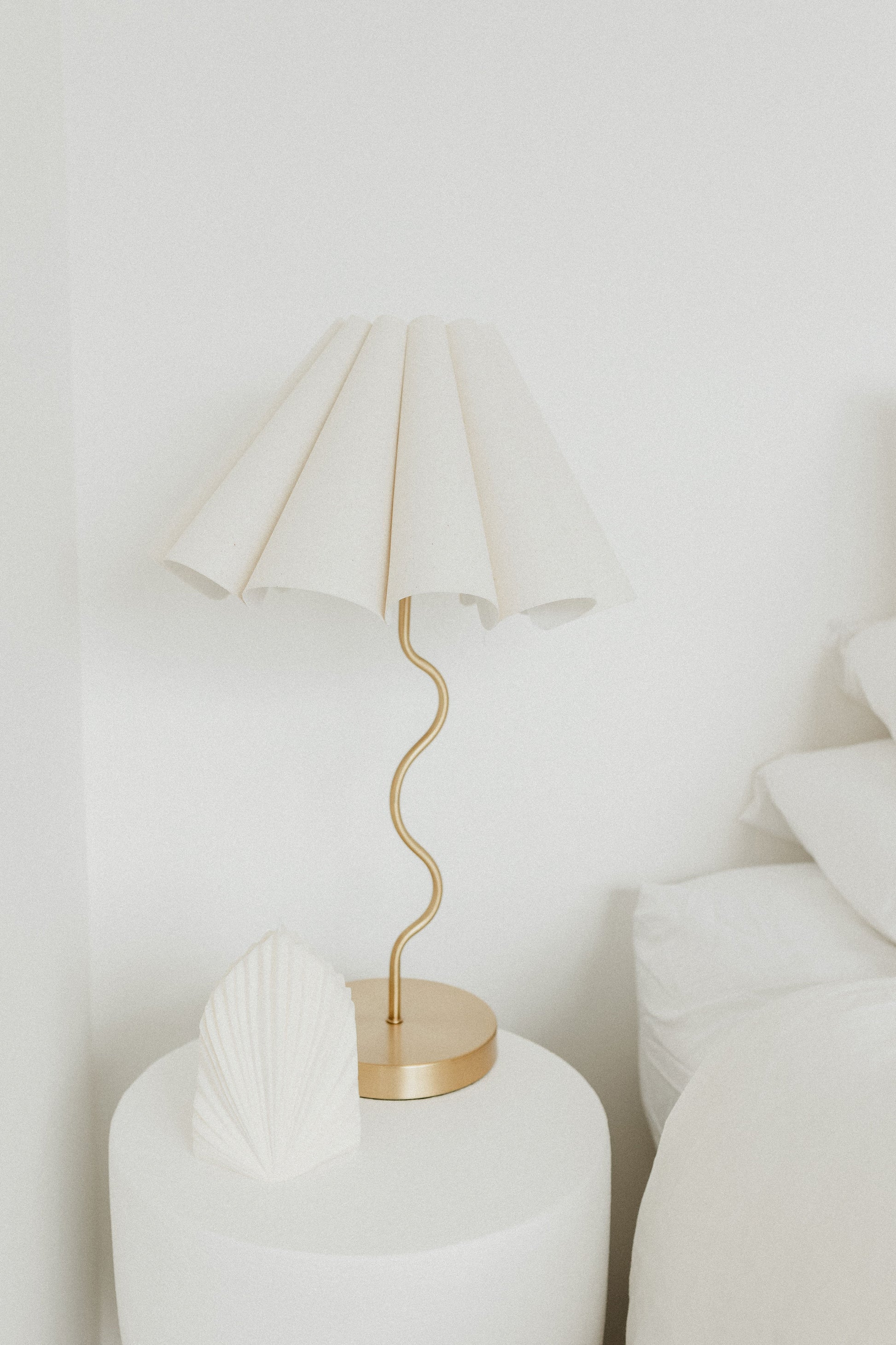 Cora Gold lamp with white shade on a white surface
