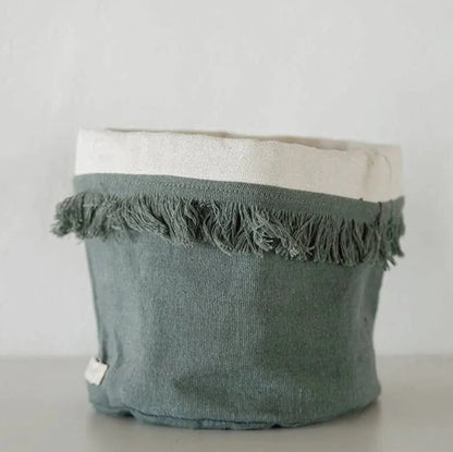 Green fabric basket with white top on a light gray background