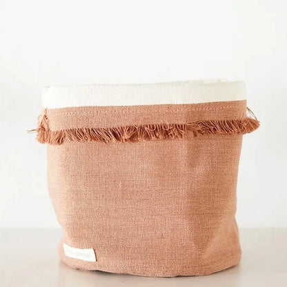 Pink woven basket with frayed edges on a white background
