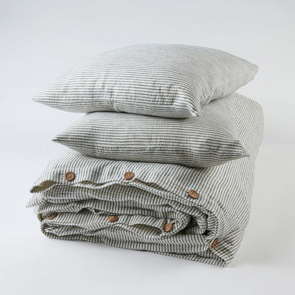 Stack of folded striped bedding with decorative buttons on a white background