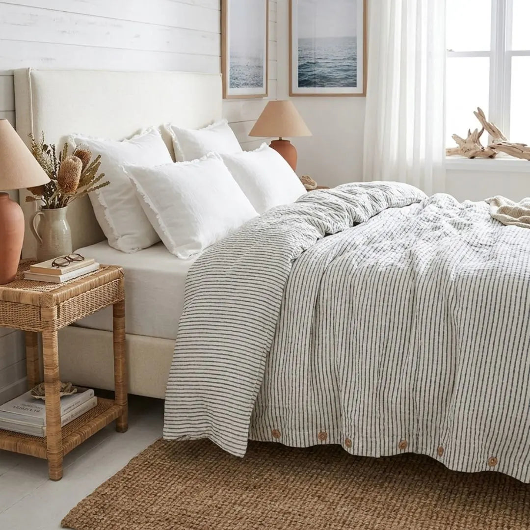 Neatly made bed with striped duvet in a well-lit bedroom.