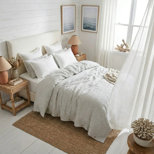 Neatly made bed with white and gray bedding in a bright bedroom.