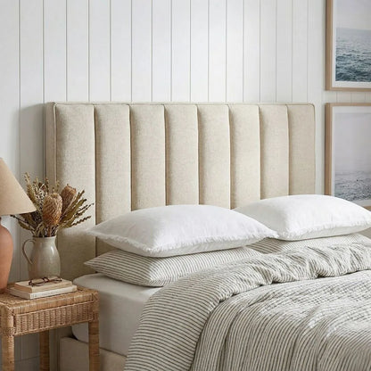 Neatly made bed with striped bedding and a textured headboard in a bedroom setting.