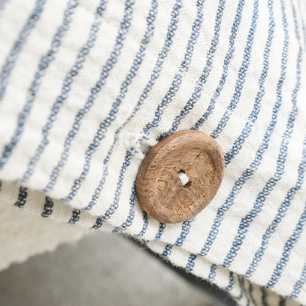 Close-up of a wooden button on a fabric with blue and white stripes.