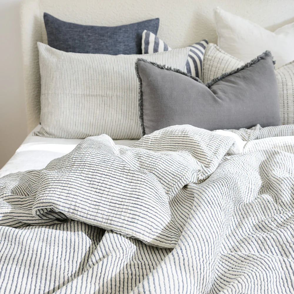Cozy bed with cotton duvet cover in white and ink blue pin stripe.