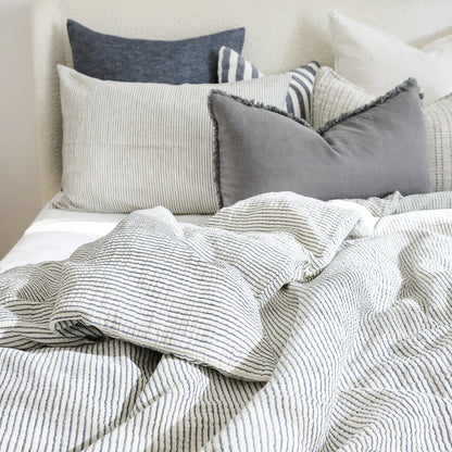 Cozy bed with cotton duvet cover in white and ink blue pin stripe.