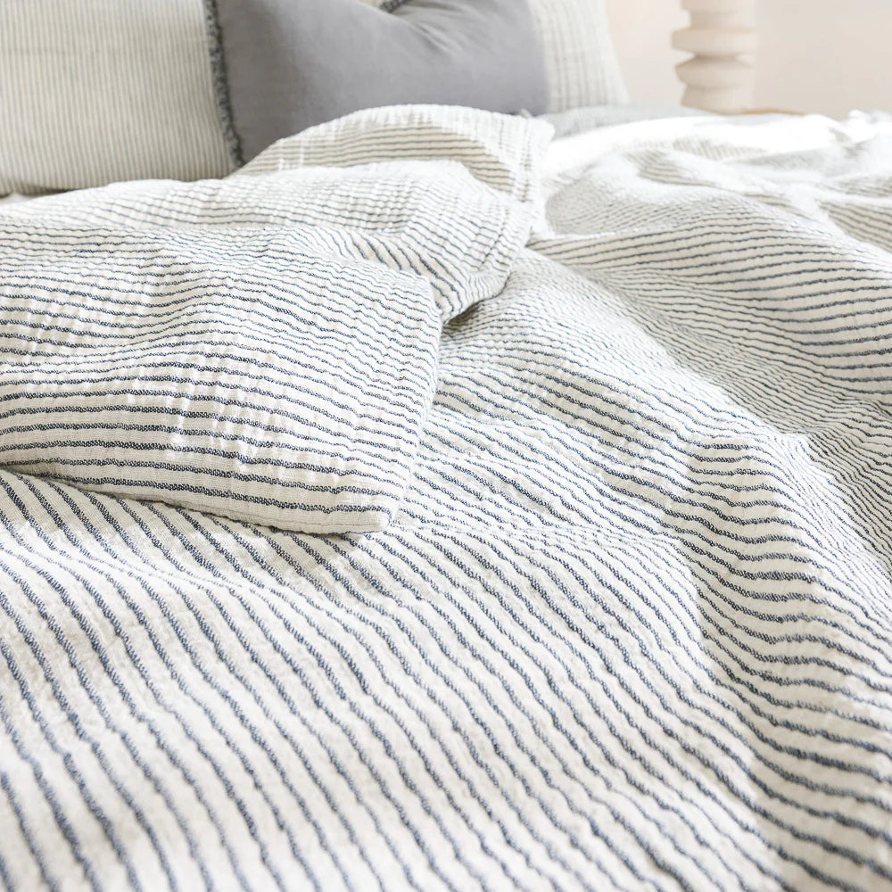 Cozy bed with cotton duvet cover in white and ink blue pin stripe.