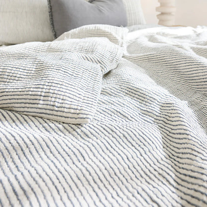 Cozy bed with cotton duvet cover in white and ink blue pin stripe.