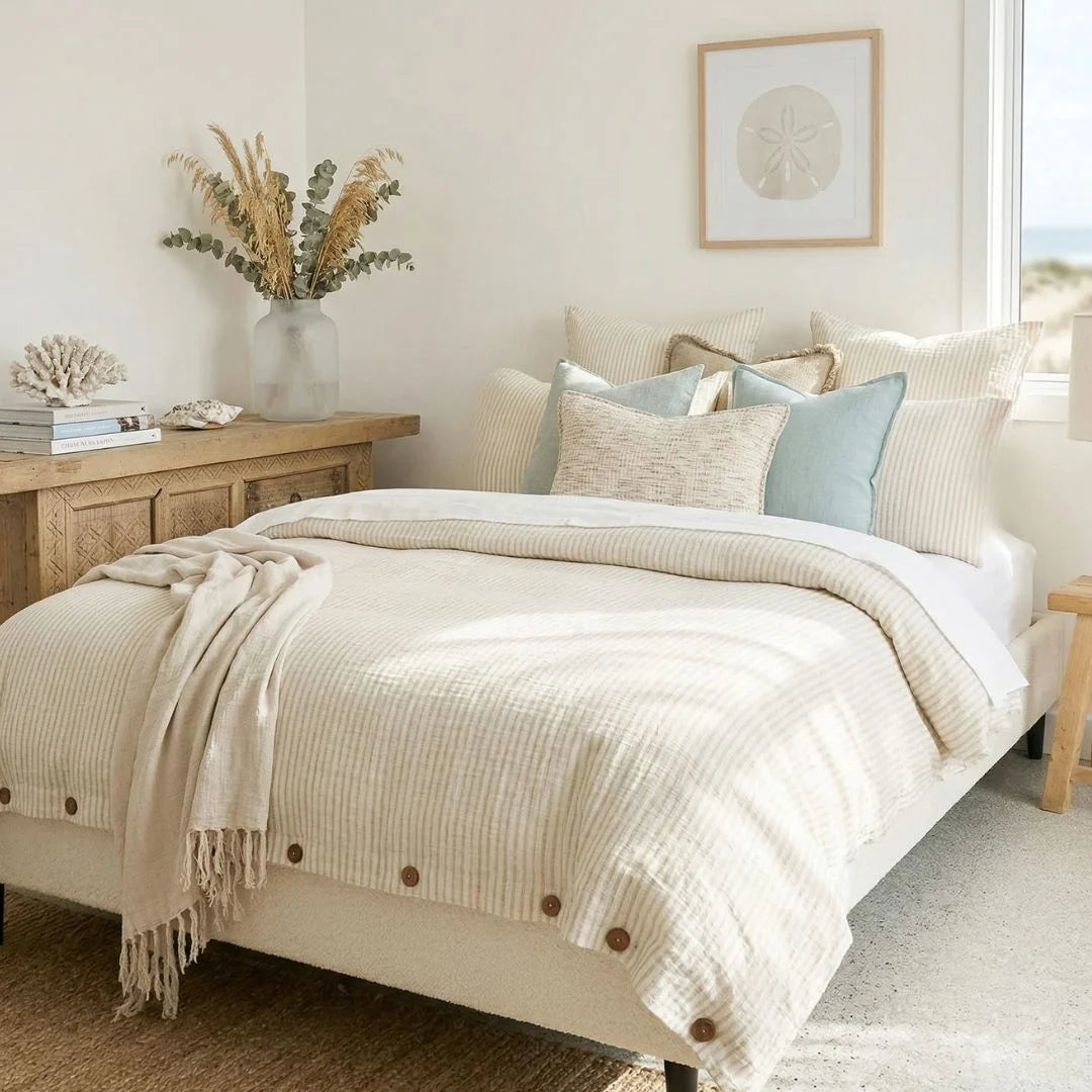 Neatly made bed with beige bedding in a bright bedroom.