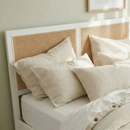 Neatly made bed with beige pillows and a woven headboard in a bedroom setting.