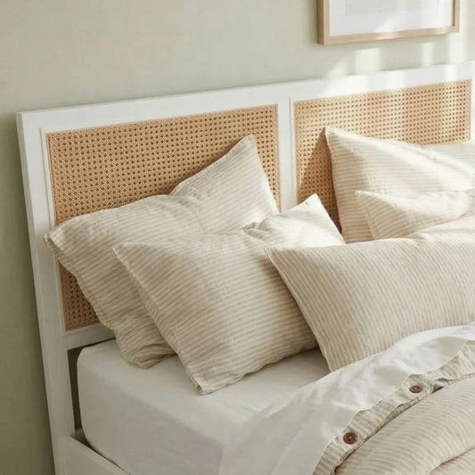 Neatly made bed with beige pillows and a woven headboard in a bedroom setting.